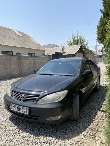 торта камри: Черный седан Toyota Camry с четырьмя дверями, оснащенный литыми