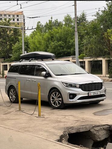 Kia: Серебристый минивэн Kia Carnival с багажником на крыше. Автомобиль