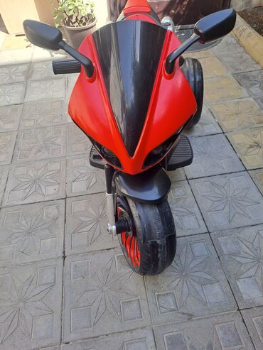 Uşaqlar üçün nəzərdə tutulmuş qırmızı elektrik motosiklet. Bu oyuncaq