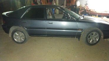 диск bbs: Хэтчбек Mazda 323F темно-серого цвета с пятью дверями. Модель 1990-х