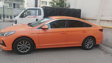 сонату: Автомобиль Hyundai Sonata оранжевого цвета. Седан имеет хромированные