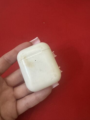Kabrolar: Ağ rəngdə, istifadə olunmuş Apple AirPods qutusu. Qutunun kiçik