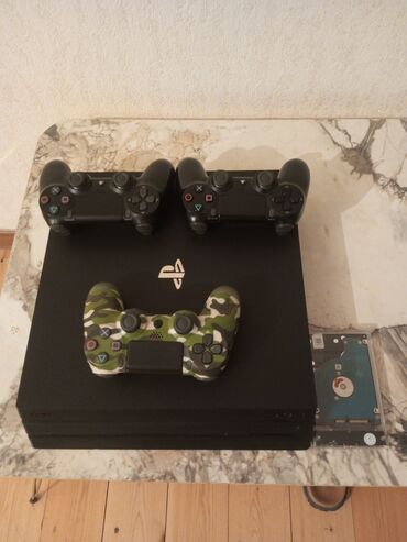 playstation oyun yazilmasi: Qara rəngdə olan PlayStation 4 pro oyun konsolu, on ədəd oyun
