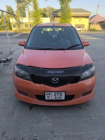 шыны на ниву: Субкомпактный хэтчбек Mazda Demio оранжевого цвета, известный своей