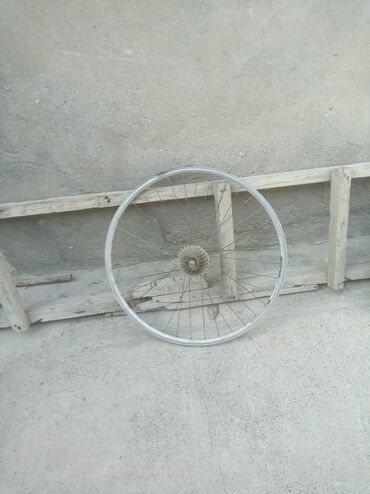 Gümüşü rəngli velosiped təkəri, dayanıqlı metal jantı və spikləri var