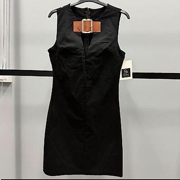 brus press: Crna mini haljina bez rukava sa upečatljivim detaljem oko vrata. Model — 1