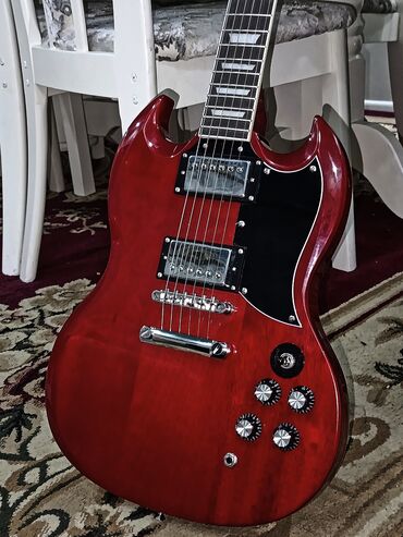 гриф акустической гитары: Электрогитара Gibson SG в красном цвете. Эта модель оснащена двумя