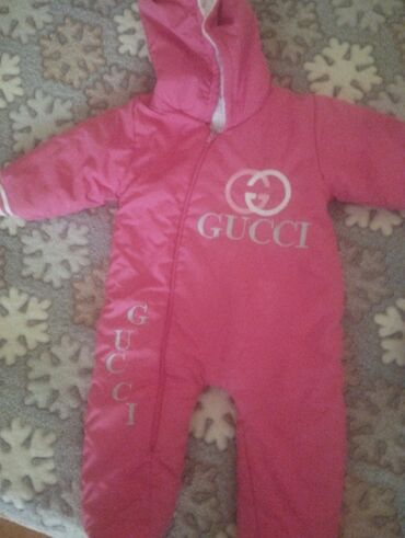 ağ uşaq krosovkaları: Çəhrayı rəngdə, kapüşonlu, Gucci loqolu uşaq kombinezonu. Ön tərəfdən