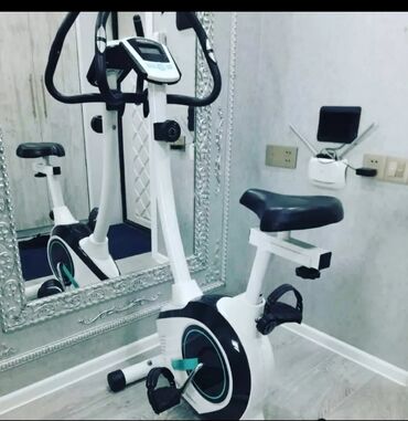 Velotrenajorlar: Ağ və qara rənglərdə olan stasionar velosiped trenajoru. Üzərində