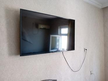 televızor: LG LED televizor, təxmini 50–55 düym ekran ölçüsü (divara asılmış) — 2