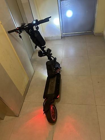Elektrikli skuter. Şəkillərdə qara rəngli, iri təkərli elektrikli