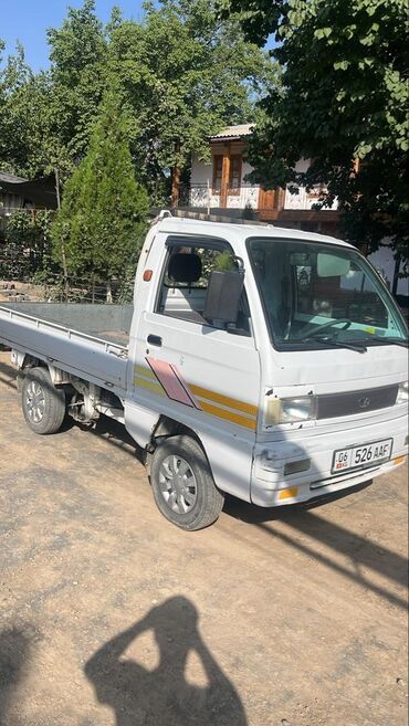 купить маленькую машину недорого: Белый пикап Daewoo лабо открытым кузовом. Автомобиль оснащен четырьмя