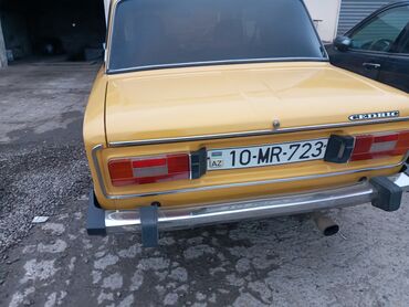 Sarı rəngli, dördqapılı sedan avtomobil. Avtomobilin arxa hissəsində