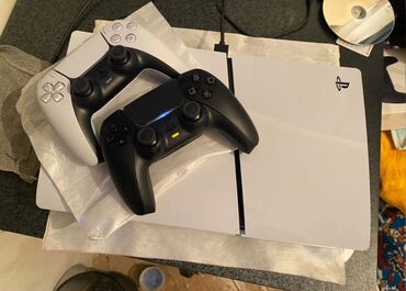 playstation evde: Ağ rəngli PlayStation 5 oyun konsolu. İki ədəd oyun idarəetmə pultu