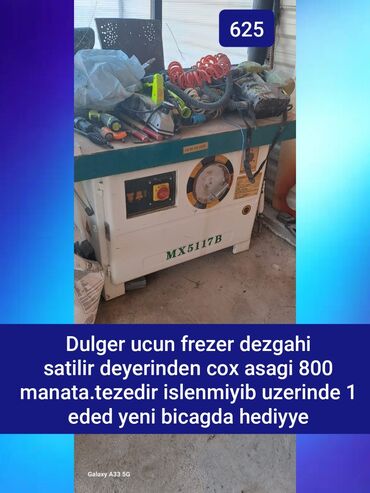 Döşəmə: Ağ rəngli MX5117B model frezer dəzgahı. Dəzgahın üst hissəsi taxta
