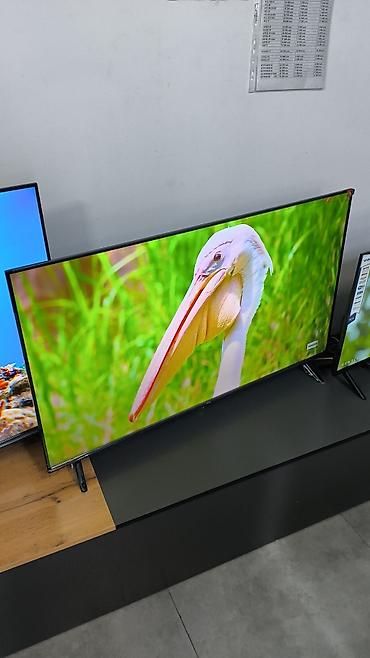 LED-телевизор с тонкими рамками и ножками-разножками по краям. Большой