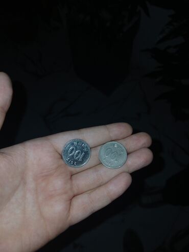 Qoruyucu plyonka və şüşələr: Əldə tutulan iki ədəd gümüşü rəngli metal sikkə. Sikkələrdən birinin
