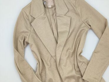 Beżowy blazer damski z długimi rękawami. Charakteryzuje się otwartym