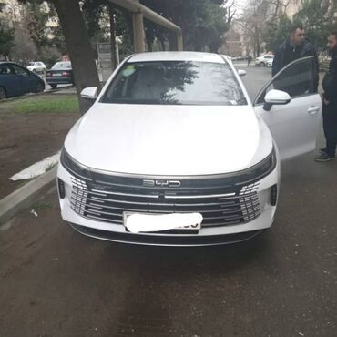BYD: BYD markalı, ağ rəngli, müasir dizaynlı avtomobil. Şəhər yollarında