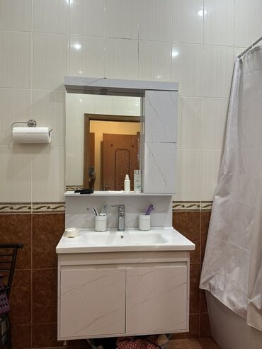 otax qapları: Ağ rəngli, mərmər naxışlı şkaf və güzgüsü olan lavabo. Şkafda əşyaları