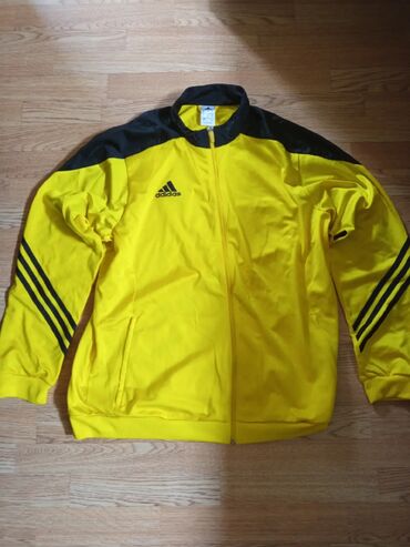 Trenajorlar: Adidas markalı, uzunqollu, sarı rəngli idman gödəkçəsi. Qara rəngli