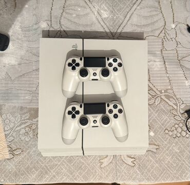 playstation oyun yazilmasi: Ağ rəngli PlayStation 4 oyun konsolu, iki ədəd ağ rəngli DualShock 4
