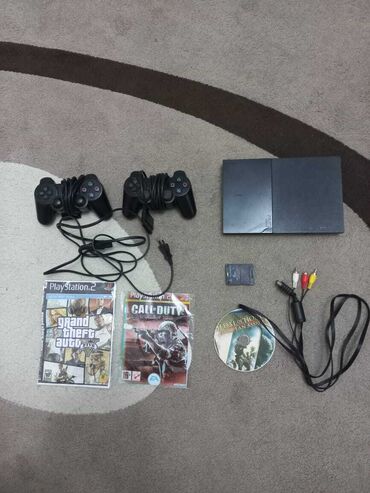 mehelle 1: Qara rəngli PlayStation 2 oyun konsolu, iki ədəd idarəetmə pultu
