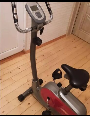 Uzunmüddətli kirayə mənzillər: Qırmızı rəngli vurğuları olan boz rəngli stasionar velosiped. LCD