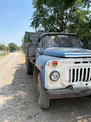 Traktor qoşquları: Mavi və ağ rəngli kabinəsi olan, taxta bortlu kuzası olan yük maşını