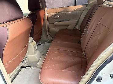 nisan note: Ağ rəngli Nissan Tiida sedan. Avtomobilin salonu açıq bej tonlarda — 7