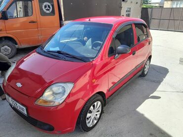 дешевые машыны: Красный хэтчбек Chevrolet Spark, припаркованный на открытой площадке