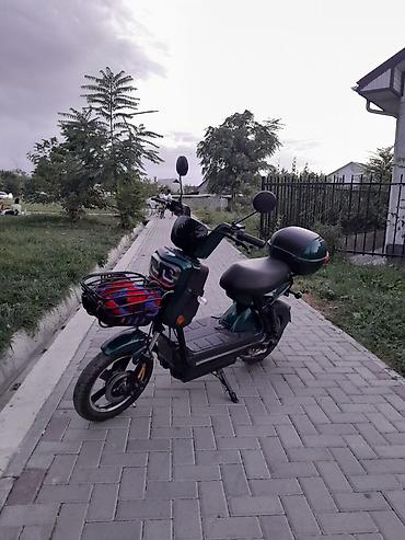 скуто: Электрический скутер (городской e-moped) в зелёном цвете. Особенности — 2