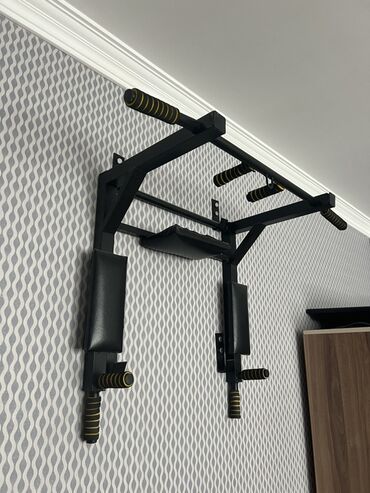 Turniklər və bruslar: Divara quraşdırılan qara rəngli turnik. Dəstəyi rahat tutmaq üçün