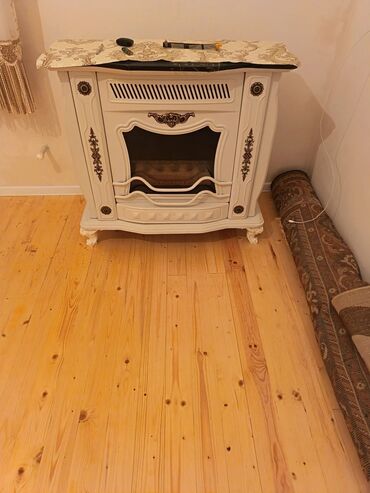 radiator alıram: Ağ rəngli, dekorativ kamin. Qəhvəyi aksesuarlarla bəzədilmişdir. Üst