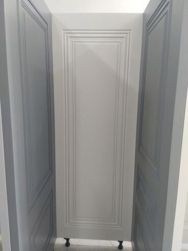 taxt bazasi: Ağ rəngdə taxta qapı paneli, mürəkkəb formalı oyma naxışlarla