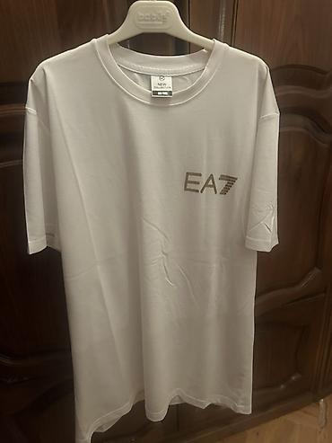 Футболки: Ağ rəngli uniseks T‑şört. Ön hissədə qızılı “EA7” loqotipi, arxa — 1