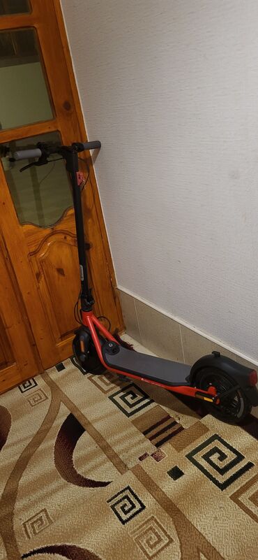 skuter təmiri: Qırmızı rəngli, yığcam Ninebot elektrik skuteri. Sürüş üçün rahat və