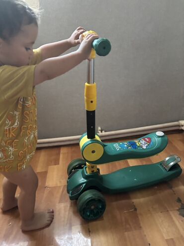 Yaşıl rəngdə uşaq skuteridir. Skuterin üç təkəri var və bu, uşağın