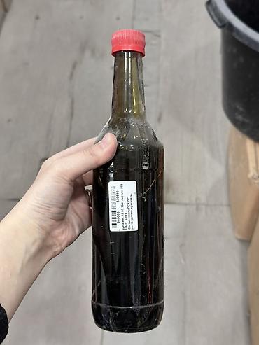 Соус темного цвета в стеклянной бутылке с красной крышкой