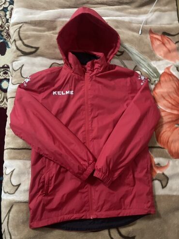 на железных номерах: Красная куртка-ветровка KELME - Спортивный дизайн с капюшоном. -