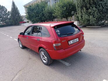 домкраты на авто: Красный хэтчбек Mazda 323F с задним спойлером и тонированными задними