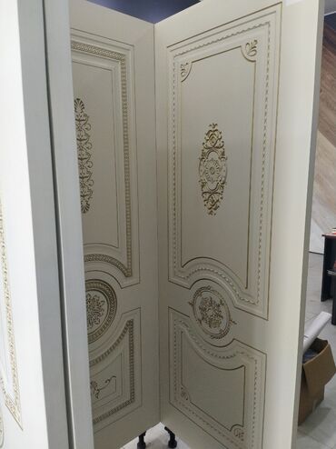 qapılar mdf: Ağ rəngdə, qızılı naxışlarla bəzədilmiş klassik üslubda qapı paneli