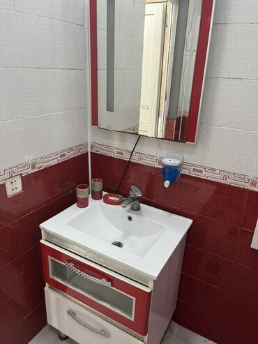 Duş başlıqları: Ağ rəngli rəfləri və qırmızı ön panelləri olan bu vannanın altındakı