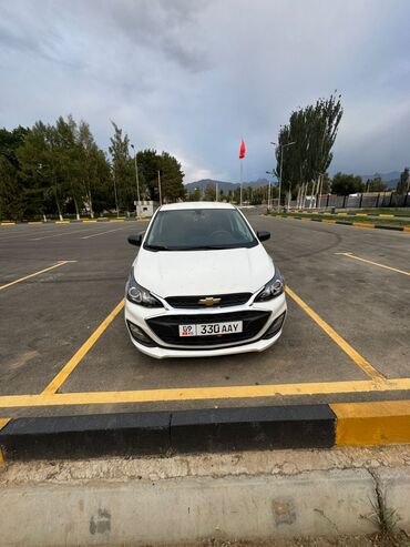 чип для авто: Белый хэтчбек Chevrolet Spark, припаркованный на асфальтированной