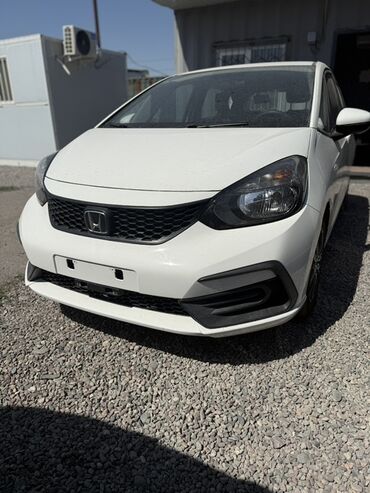маленькая машина: Белый хэтчбек Honda Fit, оснащенный черной радиаторной решеткой и