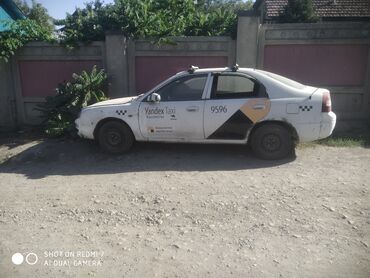 спрей скорая помощь: Kia Shuma седан белого цвета, с фирменной расклейкой “Yandex Taxi”