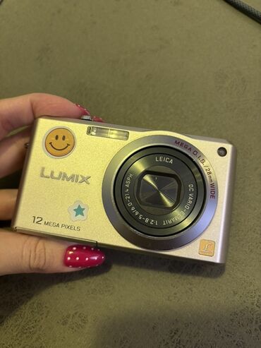 Panasonic Lumix markalı, gümüşü rəngdə rəqəmsal kamera. Cihaz optik