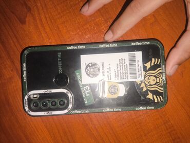 Arxa tərəfində Starbucks stikerləri olan tünd yaşıl rəngli smartfon