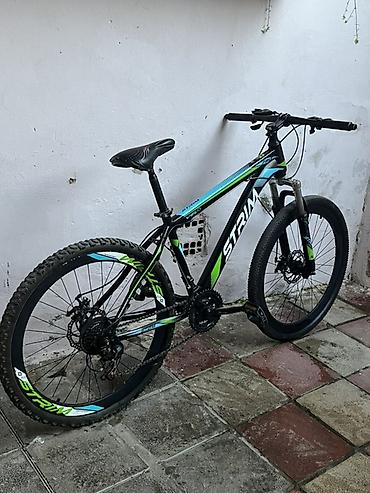 boyuk velosiped: Qara rəngli, yaşıl və mavi vurğulara malik dağ velosipedi. Velosipeddə — 4