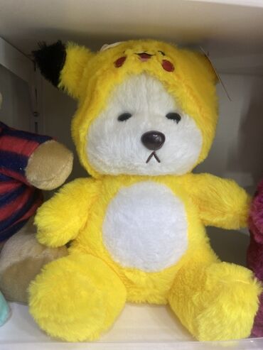 Pikachu başlıqlı sarı rəngli yumşaq oyuncaq. Oyuncağın üzərində